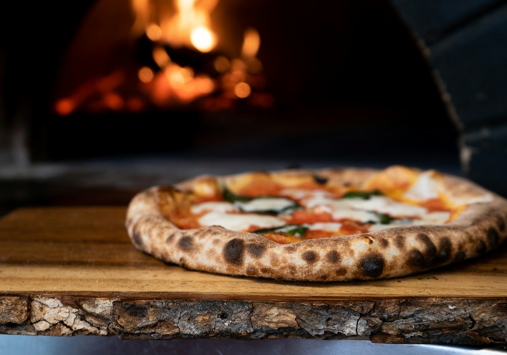 Freshly baked pizza beside a wood-fired oven